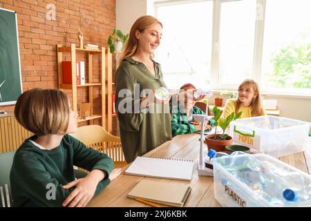 Enseignante avec des élèves triant les ordures en classe. Concept d'écologie Banque D'Images