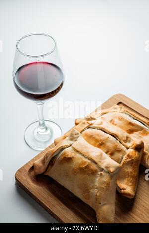 Fête du jour de l'indépendance avec empanadas de viande cuite au Chili et vin rouge sur une planche de bois. Tradition et goût Banque D'Images