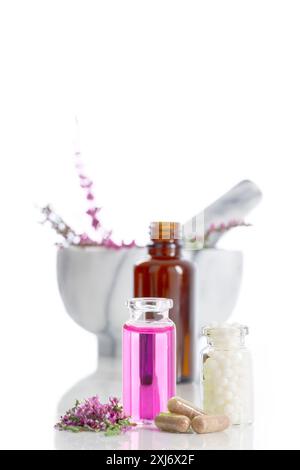 Ambiance aromathérapie avec granules, bruyère, mortier de marbre et pilon et petites bouteilles d'eau florale sur fond blanc Banque D'Images