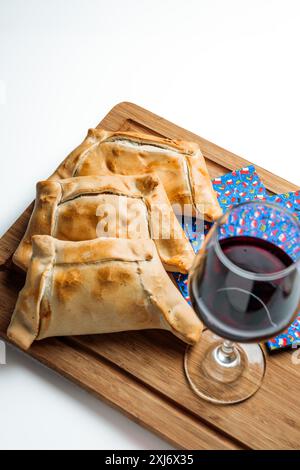 Délicieux empanadas de viande cuite chilienne avec un verre de vin rouge sur planche de bois. Tradition du jour de l'indépendance. copier l'espace Banque D'Images