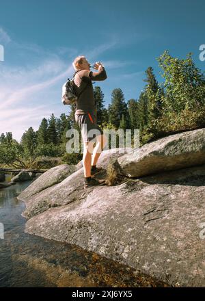 Un voyageur boit de l'eau propre dans la forêt Banque D'Images