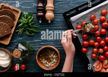 Portrait de femme part verser la sauce à l'ail sur les tomates dans la casserole de Banque D'Images