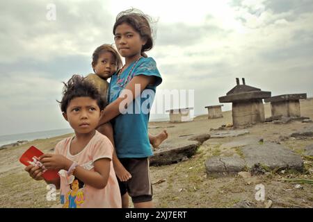 Enfants d'âge scolaire qui s'occupent d'un bébé dans le village de Ratenggaro, île de Sumba, province de Nusa Tenggara est, Indonésie. Lors d’une réunion de l’Assemblée générale en décembre 2023, les Nations Unies (ONU) soulignent la nécessité urgente d’améliorer la capacité d’adaptation, de renforcer la résilience et de réduire la vulnérabilité des peuples autochtones aux changements climatiques et aux phénomènes météorologiques extrêmes. Un document connexe indique que l’ONU encourage les États membres à « prendre des mesures qui assureront la participation pleine et effective des peuples autochtones aux processus décisionnels relatifs au changement climatique sur les questions qui les touchent,... Banque D'Images