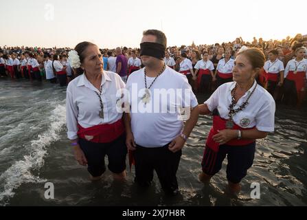 Malaga, Espagne. 16 juillet 2024. Un pénitent bandés de la fraternité 'Virgen del Carmen' est vu attendant la vierge à la plage accompagné de sa famille alors qu'il prend part à une procession. La fête annuelle 'Virgen del Carmen' dans la ville de Málaga, qui a lieu le 16 juillet, célèbre le saint patron des marins et des pêcheurs. La statue de la Vierge est portée par un groupe de croyants en costume traditionnel le long des rues avant d'être placée sur un bateau de la plage, qui navigue plus tard le long de la côte de Málaga. Crédit : SOPA images Limited/Alamy Live News Banque D'Images