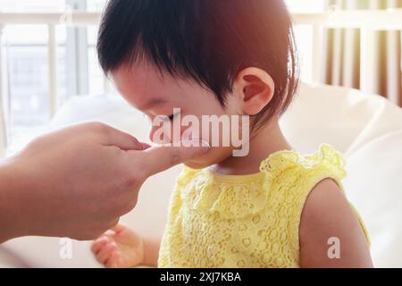 mère appliquant la crème de médecine antiallergique au visage mignon de fille asiatique avec éruption cutanée et allergie avec tache rouge cause par piqûre de moustique Banque D'Images