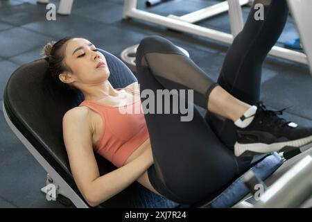 Jeune belle femme prenant un repos après sa jambe push up exercice pendant son entraînement matinal dans une salle de gym Banque D'Images