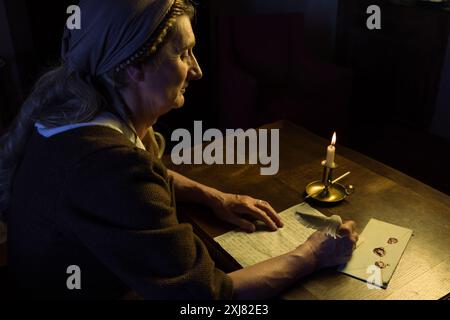 Femme dans l'écriture de tenue médiévale avec une plume plume Banque D'Images