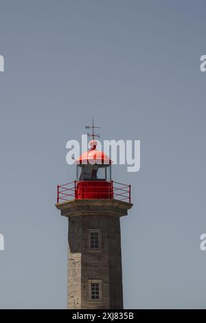 Un grand phare rouge avec une croix sur son sommet se dresse contre le ciel Banque D'Images