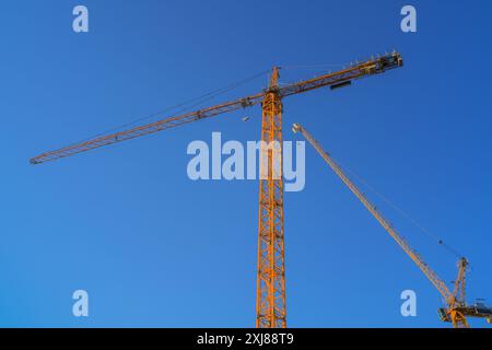 Grues à tour sur le chantier de construction contre un ciel bleu Banque D'Images