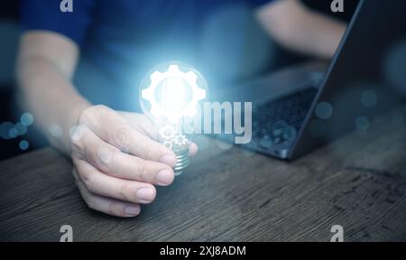 Idée et solution pour le concept d'entreprise et de technologie. Un homme tient une ampoule brillante avec des icônes d'équipement numérique dedans Banque D'Images