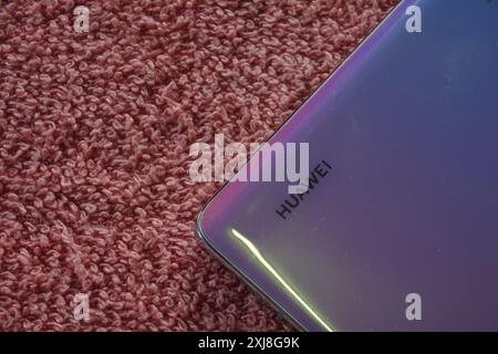 Terengganu, Malaisie - 2 août 2024 : gros plan du panneau arrière du smartphone huawei sur fond rouge. Logo Huawei sur le téléphone. Logo Huawei. Banque D'Images