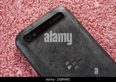 Terengganu, Malaisie - 2 août 2024 : gros plan du panneau arrière blackberry Classic q20 clavier téléphone sur fond rouge. Logo BlackBerry. Banque D'Images