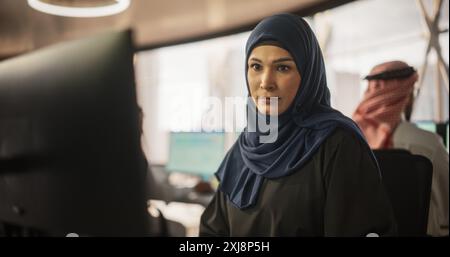 Portrait d'une jeune femme musulmane travaillant avec une équipe talentueuse de professionnels masculins dans une agence de recherche et développement technologique. Groupe de gens d'affaires traitant de projets financiers Banque D'Images