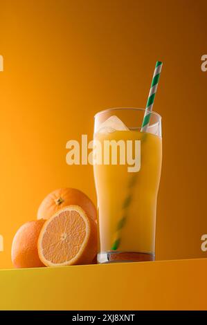 Un verre de jus d'orange frais avec des agrumes vibrants sur un fond jaune vif, mettant en valeur un attrait rafraîchissant, sain et naturel. Banque D'Images