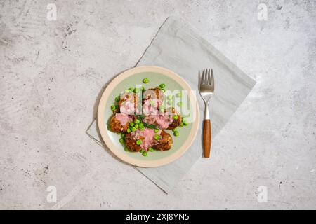 Vue de dessus des boulettes de viande avec des pois verts frais et sauce aux canneberges sur fond de pierre grise Banque D'Images