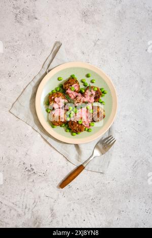 Vue de dessus de l'assiette avec boulettes de viande avec des petits pois verts frais et sauce aux canneberges sur fond de pierre grise Banque D'Images