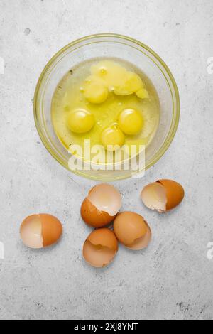 Vue de dessus des œufs de poule cassés dans un bol en verre Banque D'Images