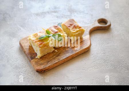 Vue aérienne de trois morceaux de tarte au fromage géorgien Achma sur planche à découper en bois Banque D'Images