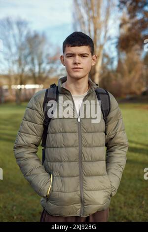 Élégance de jeunesse : beau garçon de 17 ans debout dans le parc d'automne avec pelouse verte luxuriante Banque D'Images