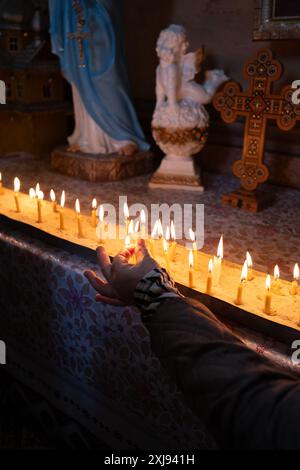 Une femme place une bougie de prière pendant une liturgie avant la commémoration des défunts à l'église orthodoxe de Kryvoryvnia. La Provody est une fête orthodoxe des morts célébrée une semaine après Pâques, et elle est aussi appelée la « Pâques de ceux qui sont décédés ». Selon la vieille tradition, après la liturgie où la nourriture est bénie, les fidèles se rendent dans les cimetières pour se régaler sur les tombes de leurs proches passés. Contrairement à la fête automnale des morts, Provody est une joyeuse célébration de la vie et de la mort. Avec la guerre en cours en Ukraine, il prend une signification particulière. Les Carpates ukrainiennes Banque D'Images