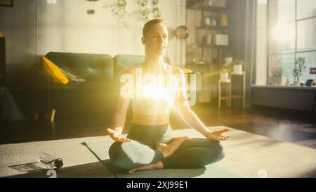 Belle femme caucasienne détendue méditant dans le salon Loft Apartment. Edité visualisation de l'énergie lumineuse accumulée dans sa poitrine. Pratique du yoga, autosoins et concept de pleine conscience. Banque D'Images