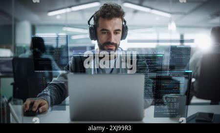 Jeune développeur de logiciels masculin hispanique travaillant dans le bureau de démarrage technologique. Spécialiste latin Programming Monitoring solutions. VFX hologramme modifier visualisation des interfaces d'encodage, Windows ouvert Banque D'Images