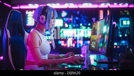 Professionnel belle femme eSports Gamer jouant 3D Shooter jeu vidéo avec graphiques modernes sur son ordinateur. Élégant futuriste Cyberpunk Gaming Neon Room avec Cosplay Gamer Girl dans les écouteurs Banque D'Images