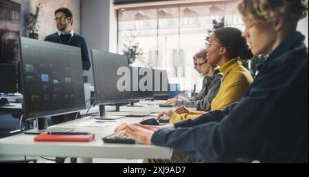 Éducateur donnant des leçons à divers groupes multiethniques d'étudiants féminins et masculins dans la salle College. Apprentissage en classe de l'informatique et du développement de logiciels. Le conférencier partage ses connaissances avec les chercheurs Banque D'Images