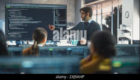 Enseignant donnant une conférence en informatique à divers groupes multiethniques d'étudiants féminins et masculins dans une salle de collège. Projection de diaporama avec code de programmation. Expliquer les technologies de l'information Banque D'Images