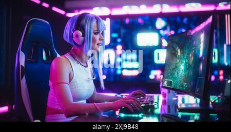 Professionnel belle femme eSports Gamer jouant à un jeu vidéo de stratégie 3D avec des graphismes modernes sur son ordinateur. Élégant futuriste Cyberpunk Gaming Neon Room avec Cosplay Gamer Girl dans les écouteurs Banque D'Images