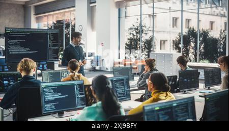 Enseignant donnant des leçons à divers groupes multiethniques d'étudiants féminins et masculins dans la salle College. Apprentissage en classe de l'informatique et du développement de logiciels. Le conférencier partage ses connaissances avec les chercheurs Banque D'Images