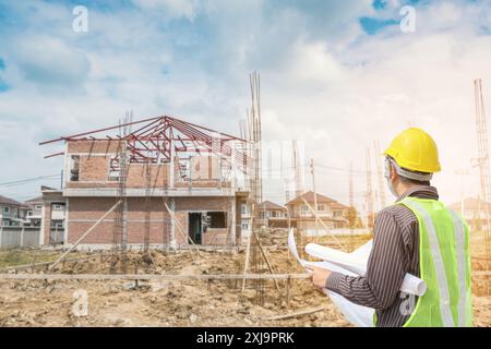 Architecte Ingénieur avec casque de protection des travailleurs et de plans de construction de bâtiment de maison papier en arrière-plan du site Banque D'Images