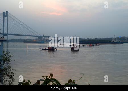 Gondoles rampant le long de la rivière Hoosely vers le pont de Vidyasagar Setu au coucher du soleil, Kolkata Calcutta, West Bengale, Inde, Asie Copyright : JohnxHarde Banque D'Images