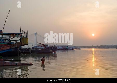 Baignade et coucher de soleil sur la rivière Hoosely avec le pont Vidyesagar Setu en arrière-plan, Kolkata Calcutta, Bengale occidental, Inde, Asie Copyright : John Banque D'Images