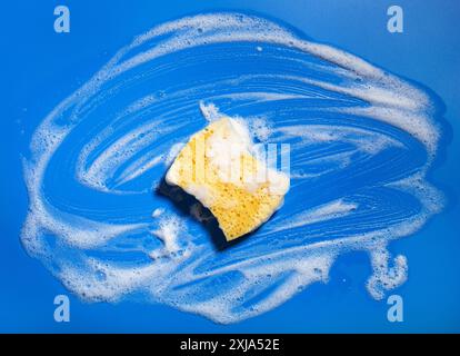 éponge de nettoyage mousse d'essuyage savon suds sur fond bleu, concept de lavage ménager Banque D'Images