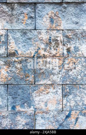 Une perspective rapprochée d'un mur de briques avec diverses taches couvrant sa surface, mettant en valeur un mélange de matériaux composites et de motifs comme des rectangles Banque D'Images