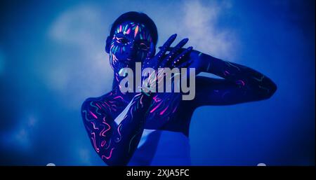 Portrait d'une jeune danseuse féminine Abstract Modern Dance performance sur une scène scénique sombre avec fond coloré Art. Photo innovante et cinématographique avec une fille hippie créative avec Body Art Banque D'Images