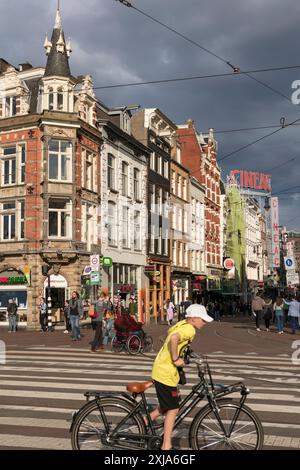 Un garçon monte son vélo de l'autre côté de la rue sur Muntplein, dans le centre d'Amsterdam, aux pays-Bas. Banque D'Images