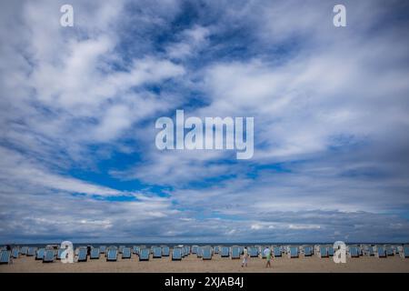 Rostock, Allemagne. 17 juillet 2024. Des chaises de plage vides se dressent par temps changeant sur la plage de Warnemünde, sur la côte de la mer Baltique. Avec des températures autour de vingt degrés, du vent et de brèves averses de pluie, le temps estival dans le nord de l'Allemagne montre son côté plutôt hostile. Crédit : Jens Büttner/dpa/Alamy Live News Banque D'Images