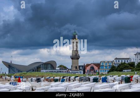 Rostock, Allemagne. 17 juillet 2024. Des nuages de pluie sombres dérivent sur la plage de Warnemünde et le phare historique sur la côte de la mer Baltique par temps changeant. Avec des températures d’une vingtaine de degrés, du vent et de brèves averses de pluie, le temps estival dans le nord de l’Allemagne montre son côté plutôt hostile. Crédit : Jens Büttner/dpa/Alamy Live News Banque D'Images