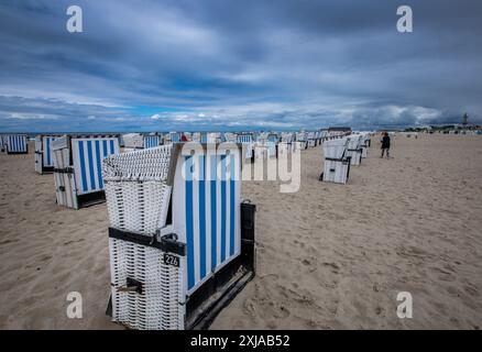 Rostock, Allemagne. 17 juillet 2024. Des chaises de plage vides se dressent par temps changeant sur la plage de Warnemünde, sur la côte de la mer Baltique. Avec des températures autour de vingt degrés, du vent et de brèves averses de pluie, le temps estival dans le nord de l'Allemagne montre son côté plutôt hostile. Crédit : Jens Büttner/dpa/Alamy Live News Banque D'Images