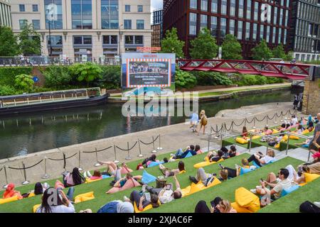 Londres, Angleterre, Royaume-Uni. 17 juillet 2024. Les gens regardent une projection au cinéma Everyman en plein air sur le gazon artificiel sur les marches de Granary Square à côté de Regent's canal à King's Cross par une chaude journée. Une alerte sanitaire a été émise en Angleterre car les températures devraient atteindre 30 °C vendredi. (Crédit image : © Vuk Valcic/ZUMA Press Wire) USAGE ÉDITORIAL SEULEMENT! Non destiné à UN USAGE commercial ! Banque D'Images