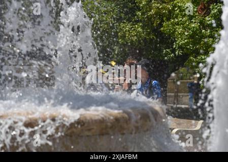 Une vague de chaleur prolongée approche du pic à Athènes les gens passent devant une fontaine sur la place Syntagma alors qu'une vague de chaleur prolongée approche du pic à Athènes. Athènes Grèce Copyright : xNicolasxKoutsokostasxNicolasxKoutsokostasx DSC 202407170105 Banque D'Images