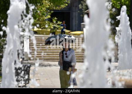 Une vague de chaleur prolongée approche du pic à Athènes Un touriste tient un parapluie pour se protéger en passant devant une fontaine sur la place Syntagma alors qu'une vague de chaleur prolongée approche du pic à Athènes. Athènes Grèce Copyright : xNicolasxKoutsokostasxNicolasxKoutsokostasx DSC 202407170428 Banque D'Images