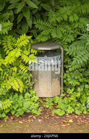 poubelle dans les buissons d'un parc Banque D'Images