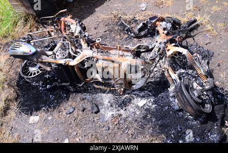 Moto brûlée couchée sur le sol avec des débris de cendres sombres à Manchester, Royaume-Uni Banque D'Images