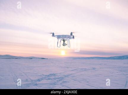 Drone volant au-dessus du lac gelé Baïkal au coucher du soleil. Banque D'Images