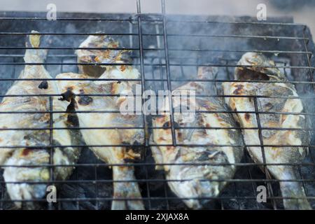 Cuisson du poisson en plein air. Cuisson et rôtissage du poisson sur barbecue. Poisson grillé sur charbon de bois. Idée de concept d'heure d'été et d'alimentation saine. Vue de dessus. Banque D'Images