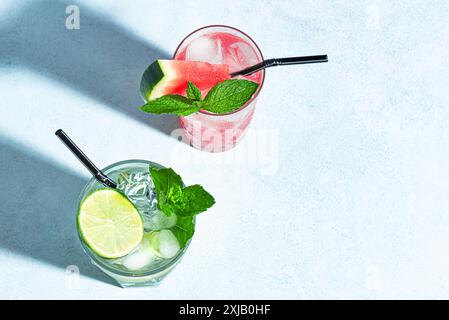 Cocktails d'été à la mode avec pastèque, citron vert, menthe et glace sur fond bleu, vue de dessus, espace de copie. Cocktail d'été, concept de bar de plage. Banque D'Images