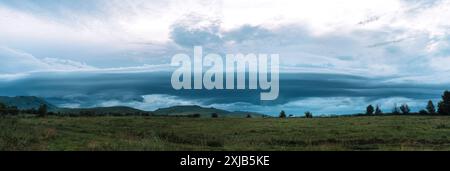 De sombres nuages de pluie pendent au-dessus des montagnes et des maisons de village Banque D'Images